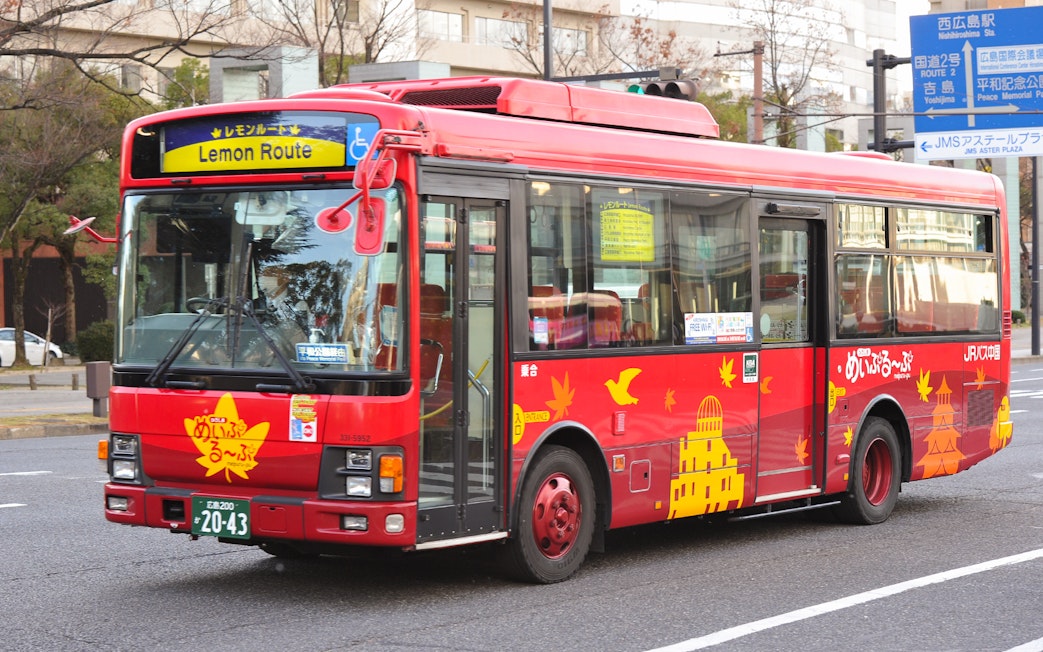 Red Hiroshima tourist bus on Lemon Route with city landmarks depicted.