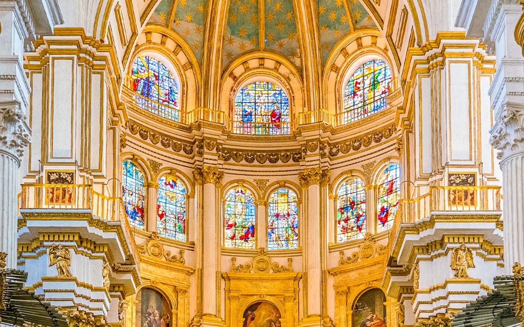 Granada Cathedral interior with colorful stained glass windows.
