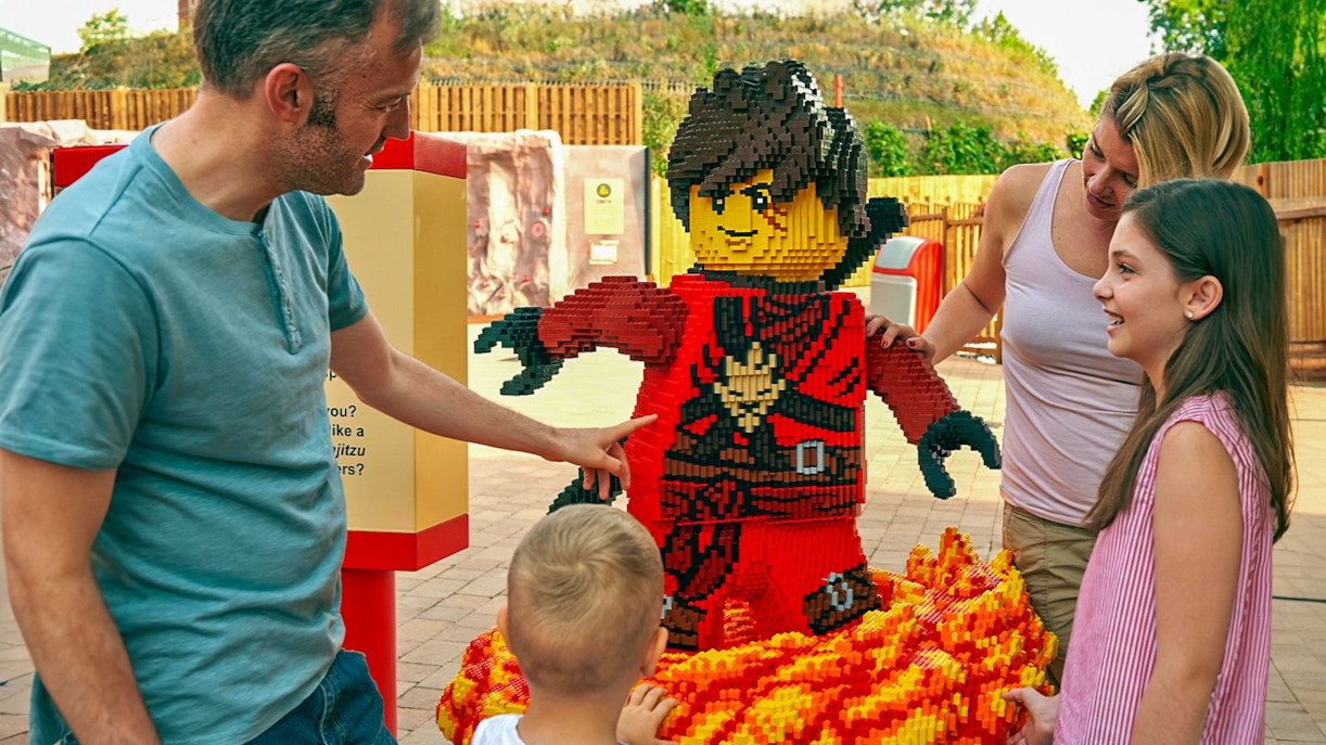 Family interacting with LEGO ninja sculpture at LEGOLAND Windsor Resort.