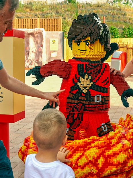 Family interacting with LEGO ninja sculpture at LEGOLAND Windsor Resort.