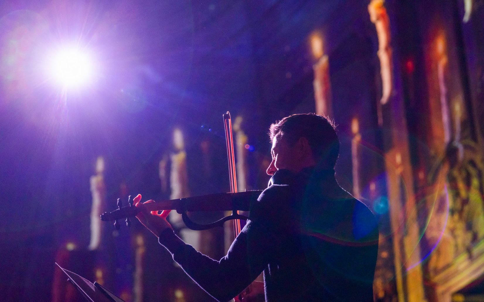 Performer playing violin at Clérigos Church light show, Porto.