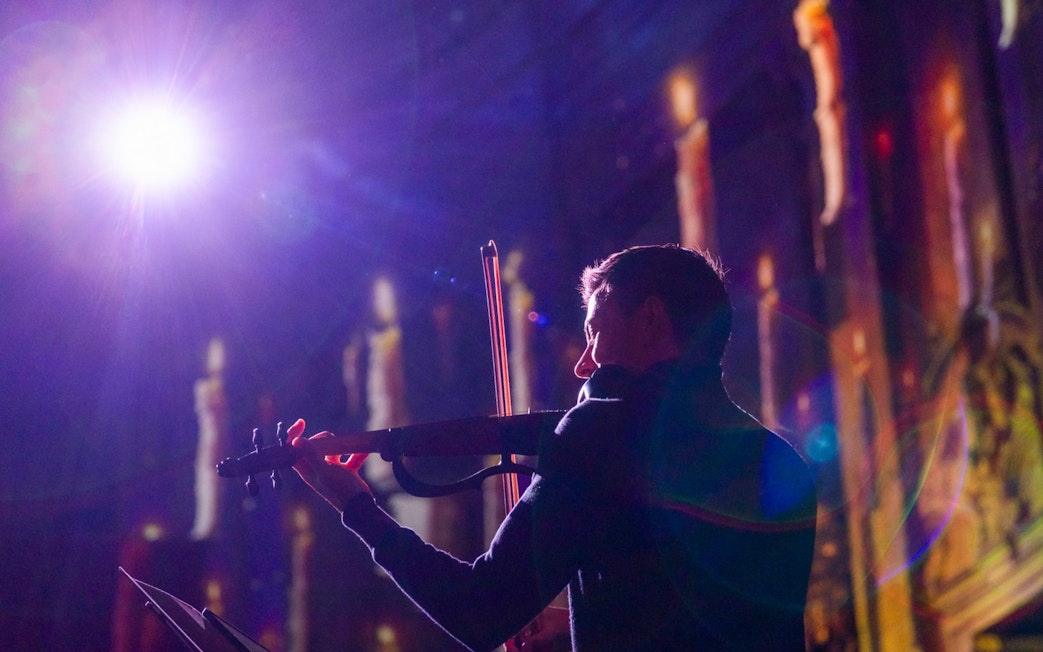 Performer playing violin at Clérigos Church light show, Porto.
