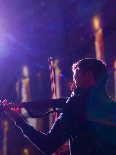 Performer playing violin at Clérigos Church light show, Porto.