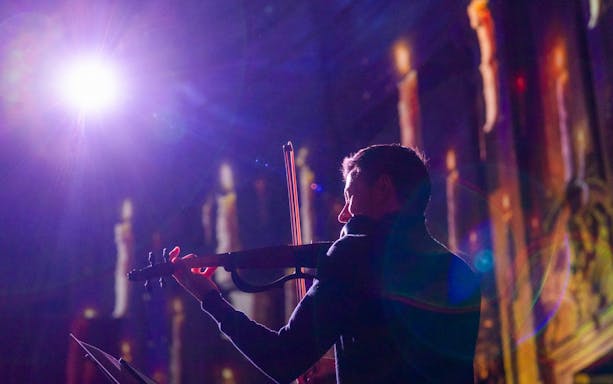 Performer playing violin at Clérigos Church light show, Porto.