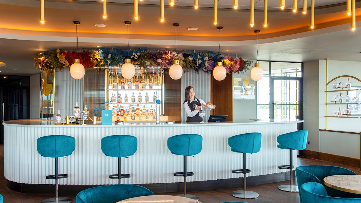 Bartender serving drinks at Plaza Premium Lounge bar in Edinburgh Airport.