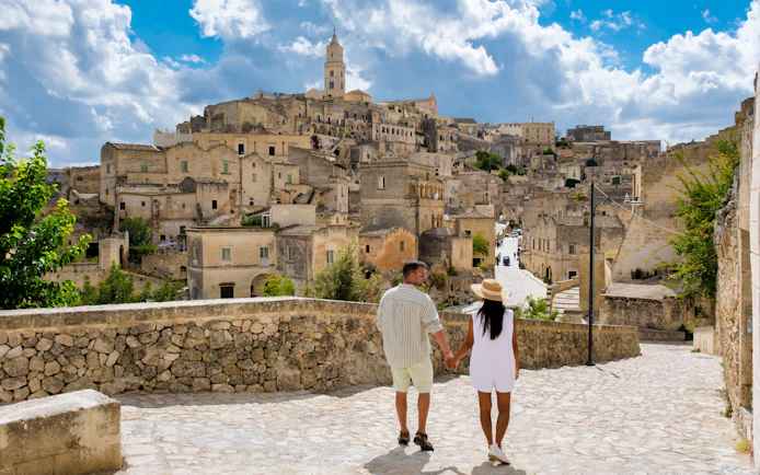 Couple walking through historic stone streets of Matera, Italy.