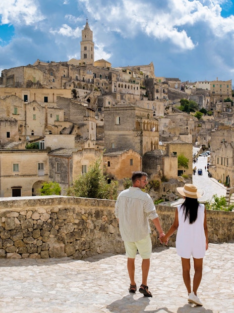Couple walking through historic stone streets of Matera, Italy.