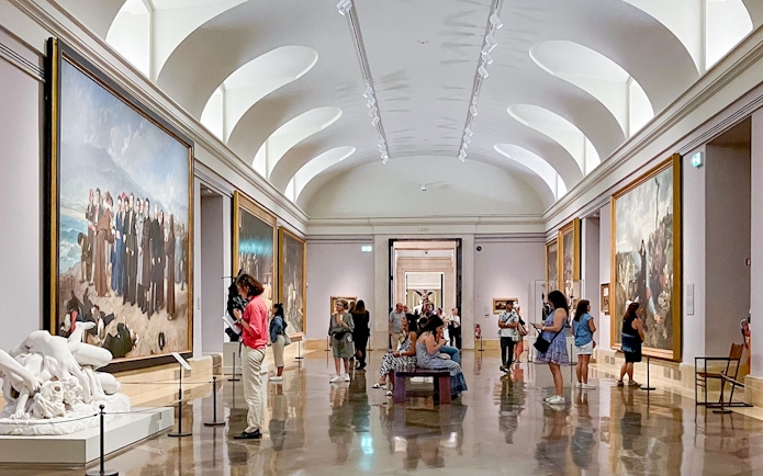 Visitors exploring art galleries inside the Prado Museum, Madrid.