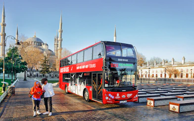 Tourists boarding a red double-decker bus near the Blue Mosque in Istanbul.