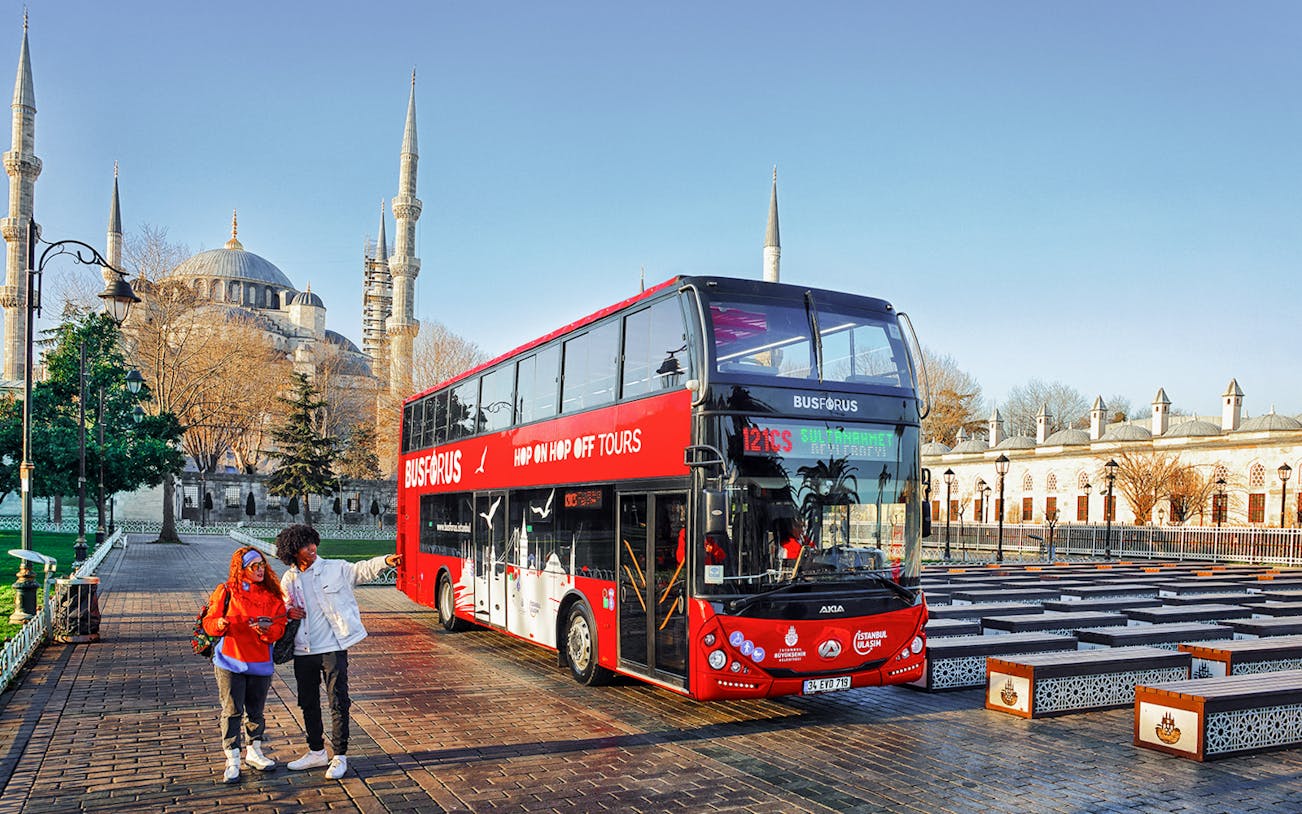 Tourists boarding a red double-decker bus near the Blue Mosque in Istanbul.