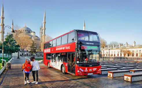 Tourists boarding a red double-decker bus near the Blue Mosque in Istanbul.