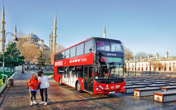 Tourists boarding a red double-decker bus near the Blue Mosque in Istanbul.