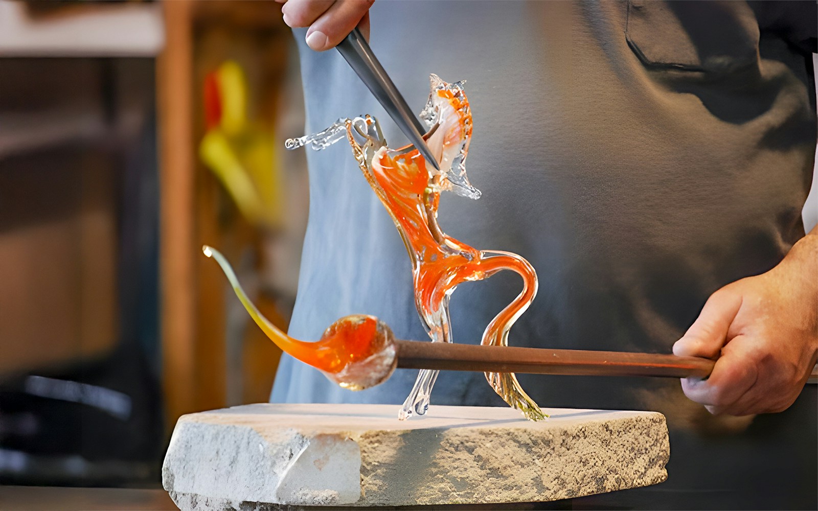Murano glassblower shaping molten glass sculpture in Murano workshop.
