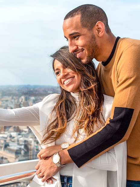 Couple taking a selfie on the London Eye with cityscape view.