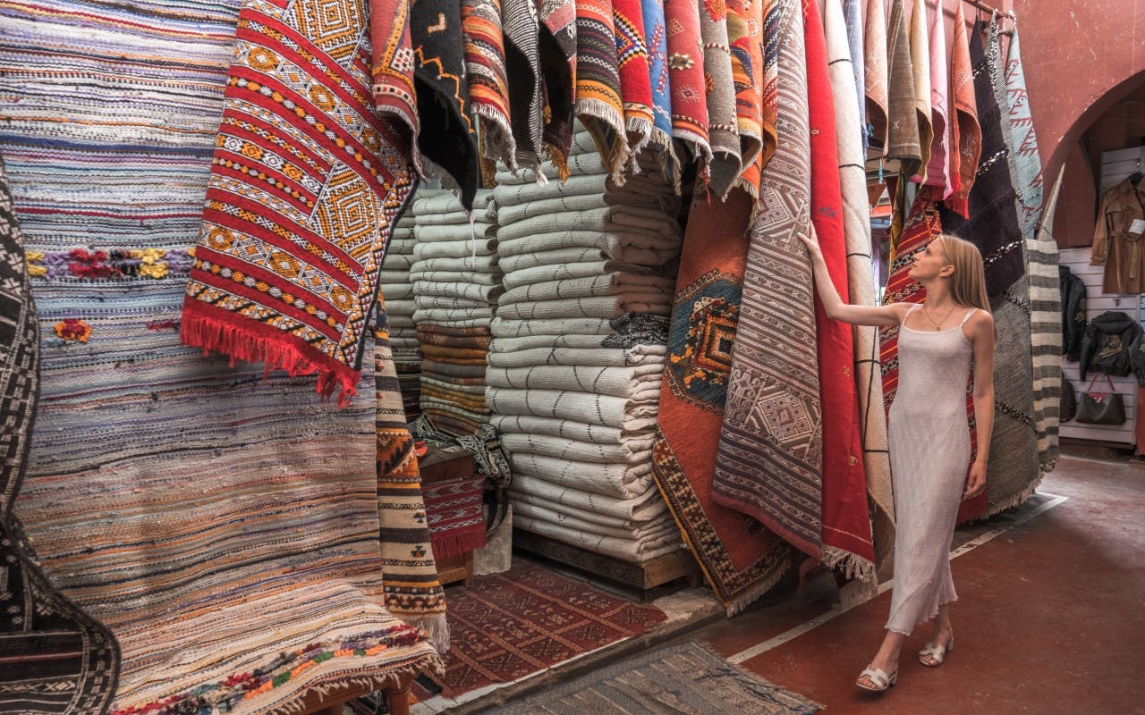 Woman exploring traditional Moroccan rugs in Agadir market.