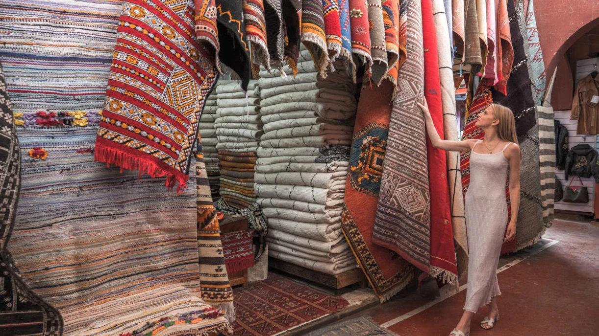 Woman exploring traditional Moroccan rugs in Agadir market.