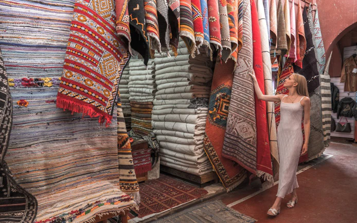 Woman exploring traditional Moroccan rugs in Agadir market.