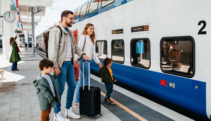Family with luggage at a train station preparing for vacation departure.