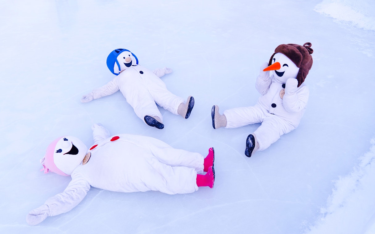 Snowmen in costumes playing on ice at Snowman World, Santa Claus Village.