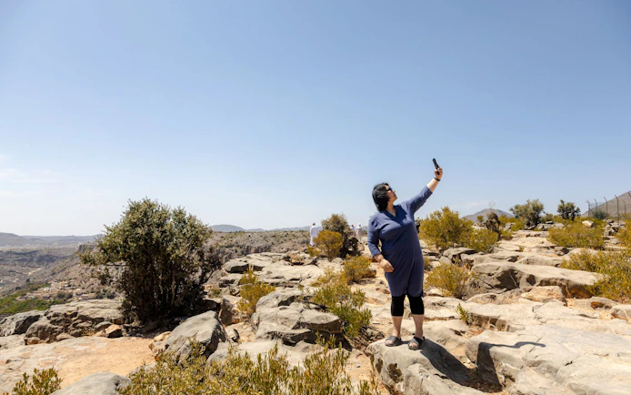 Tourist taking a selfie on rocky terrain in Jebel Akhdar, Muscat.