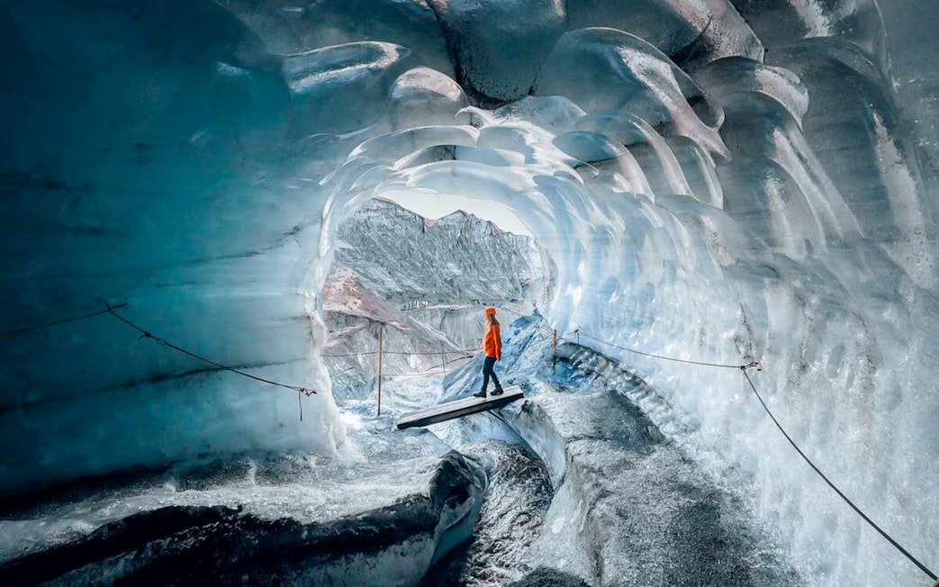Guests walking inside Katla Ice Cave, Iceland, surrounded by blue ice walls.