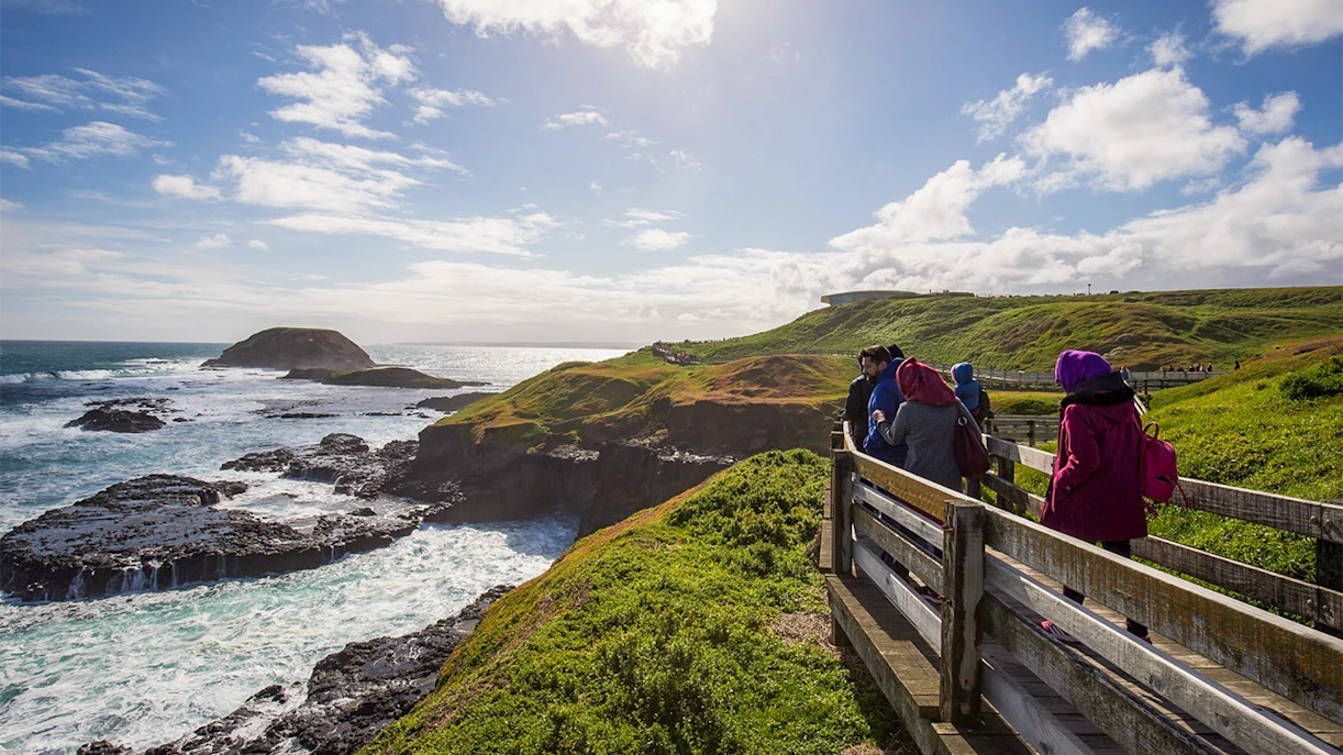 Visitors walking along Nobbies Lookout boardwalk with ocean and coastal views, Phillip Island.