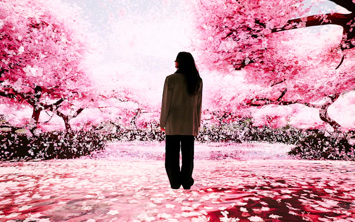 Person standing in immersive cherry blossom exhibit at Mercer Labs: Museum Of Art & Technology.