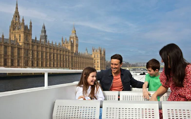 Family enjoying a London HOHO cruise with the Houses of Parliament in the background.