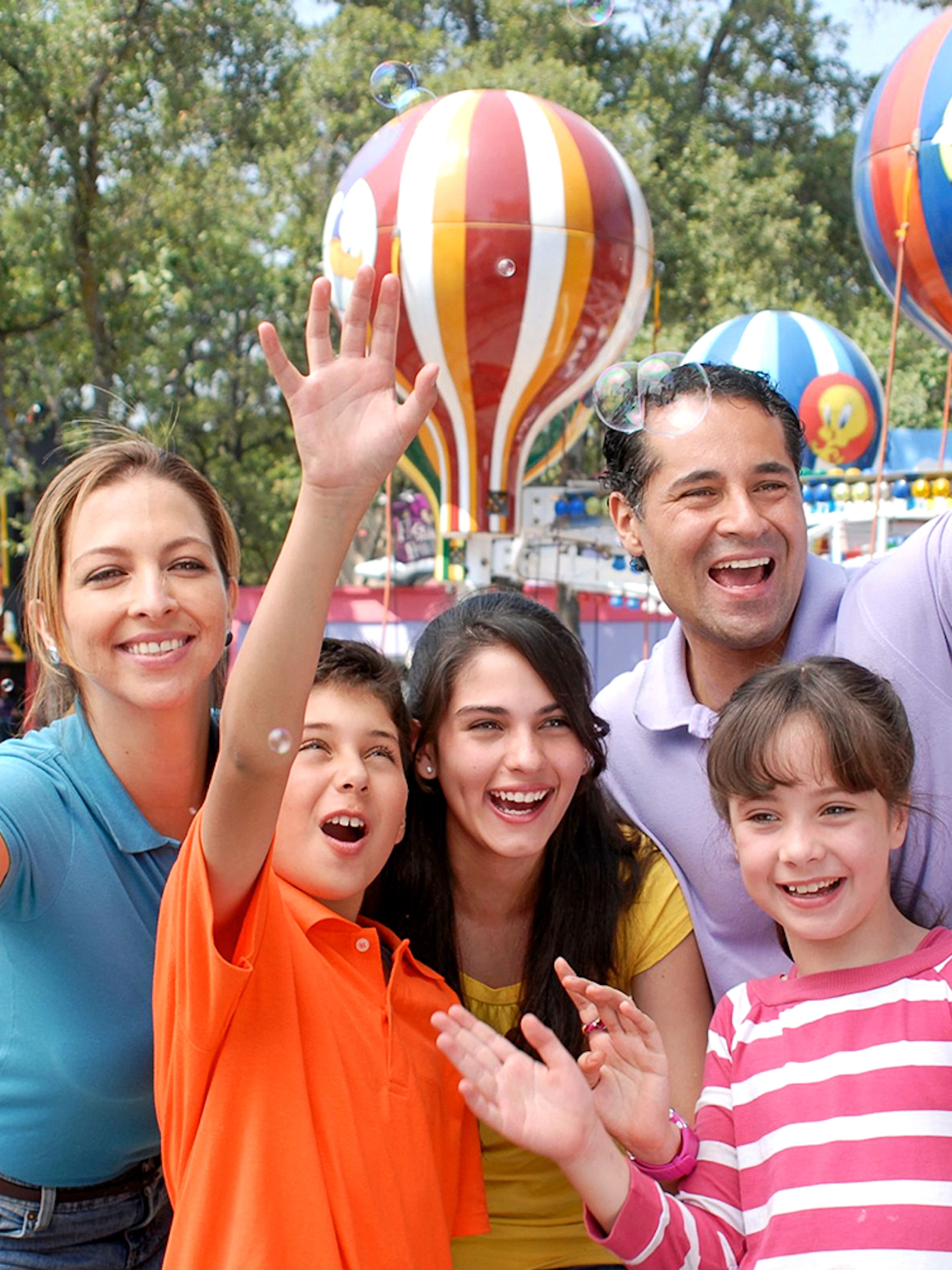 Family enjoying rides at Six Flags Great Adventure with colorful balloons in the background.