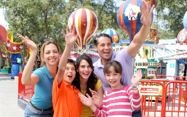 Family enjoying rides at Six Flags Great Adventure with colorful balloons in the background.