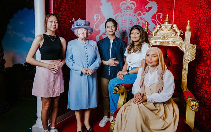 Tourists with Queen wax figure at Madame Tussauds Singapore.