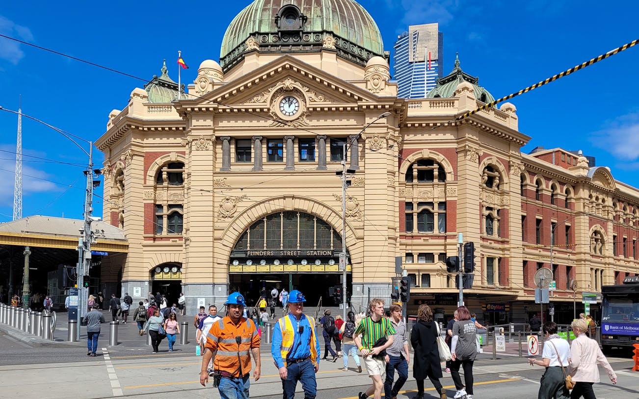 Flinders Street Station in Melbourne with pedestrians crossing the street.