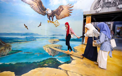 Visitors at 3D Art Langkawi interact with an optical illusion of an eagle and floating islands.
