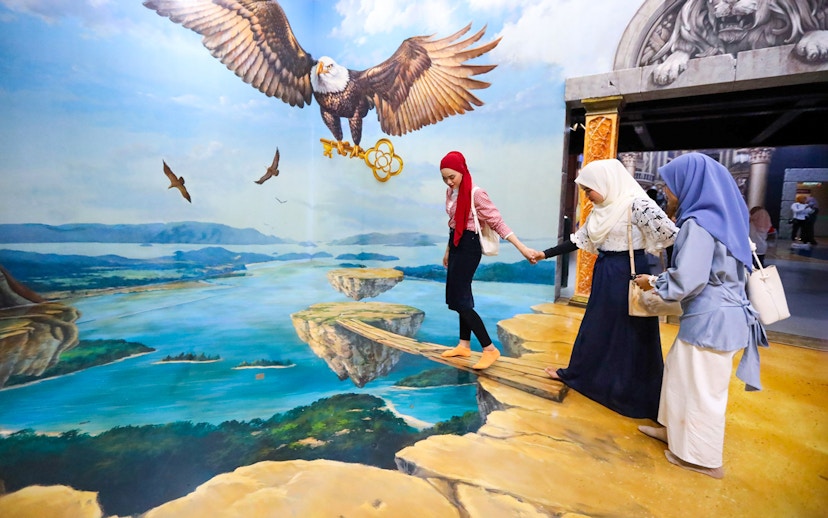 Visitors at 3D Art Langkawi interact with an optical illusion of an eagle and floating islands.