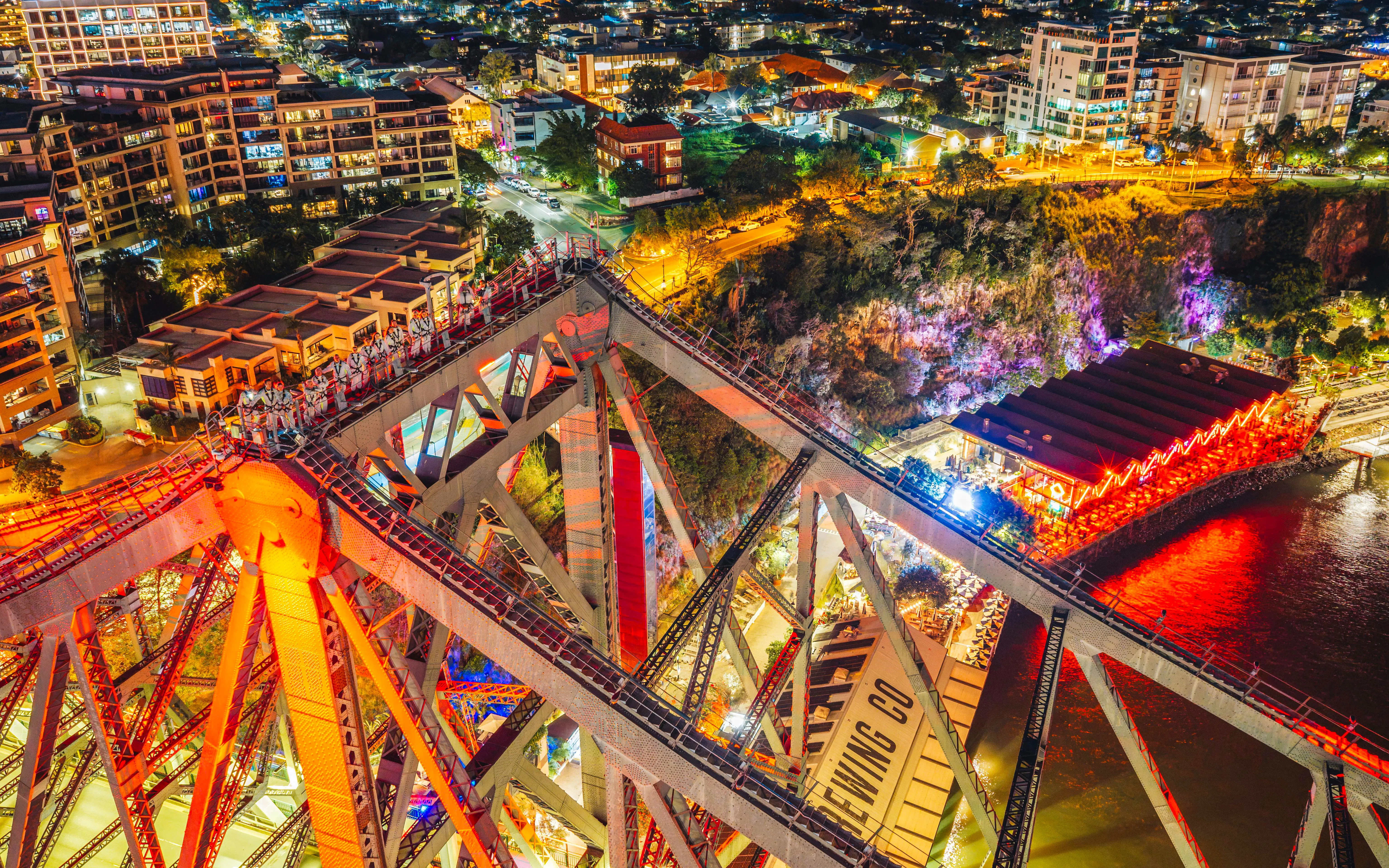 Climbers on Story Bridge at night with city lights in Brisbane, Australia.