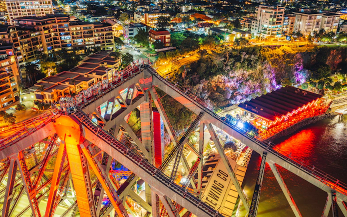 Climbers on Story Bridge at night with city lights in Brisbane, Australia.