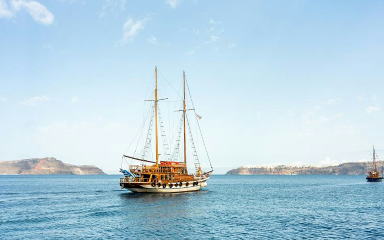 Santorini volcanic islands boat tour with view of caldera, hot springs, and Thirassia in background.