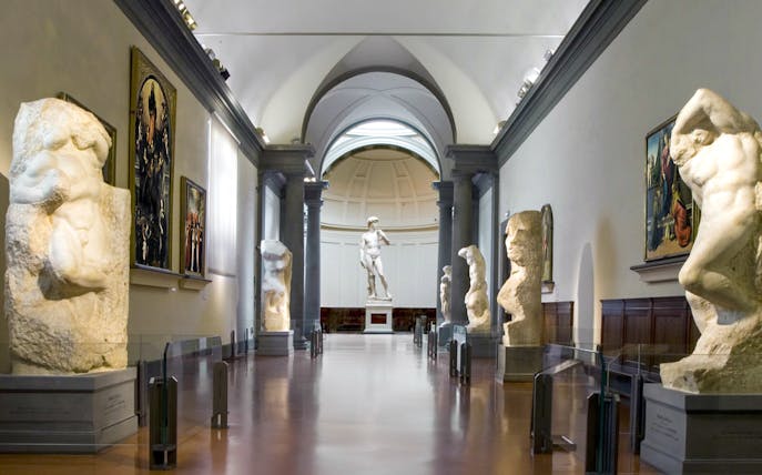 Statues and paintings in a gallery with Michelangelo's David at Academia Gallery, Florence.