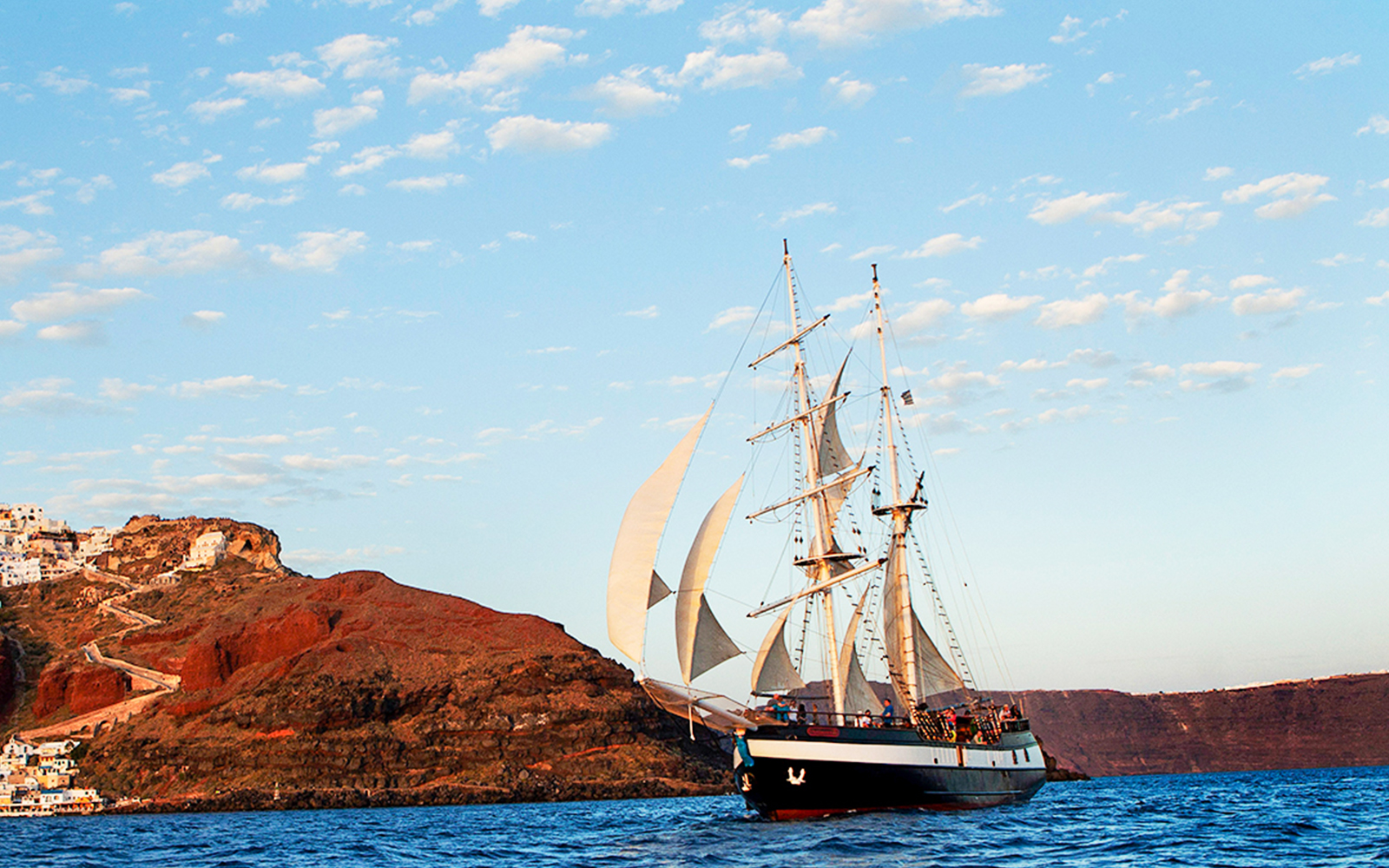 Sailing ship near volcanic island at sunset during dinner cruise.