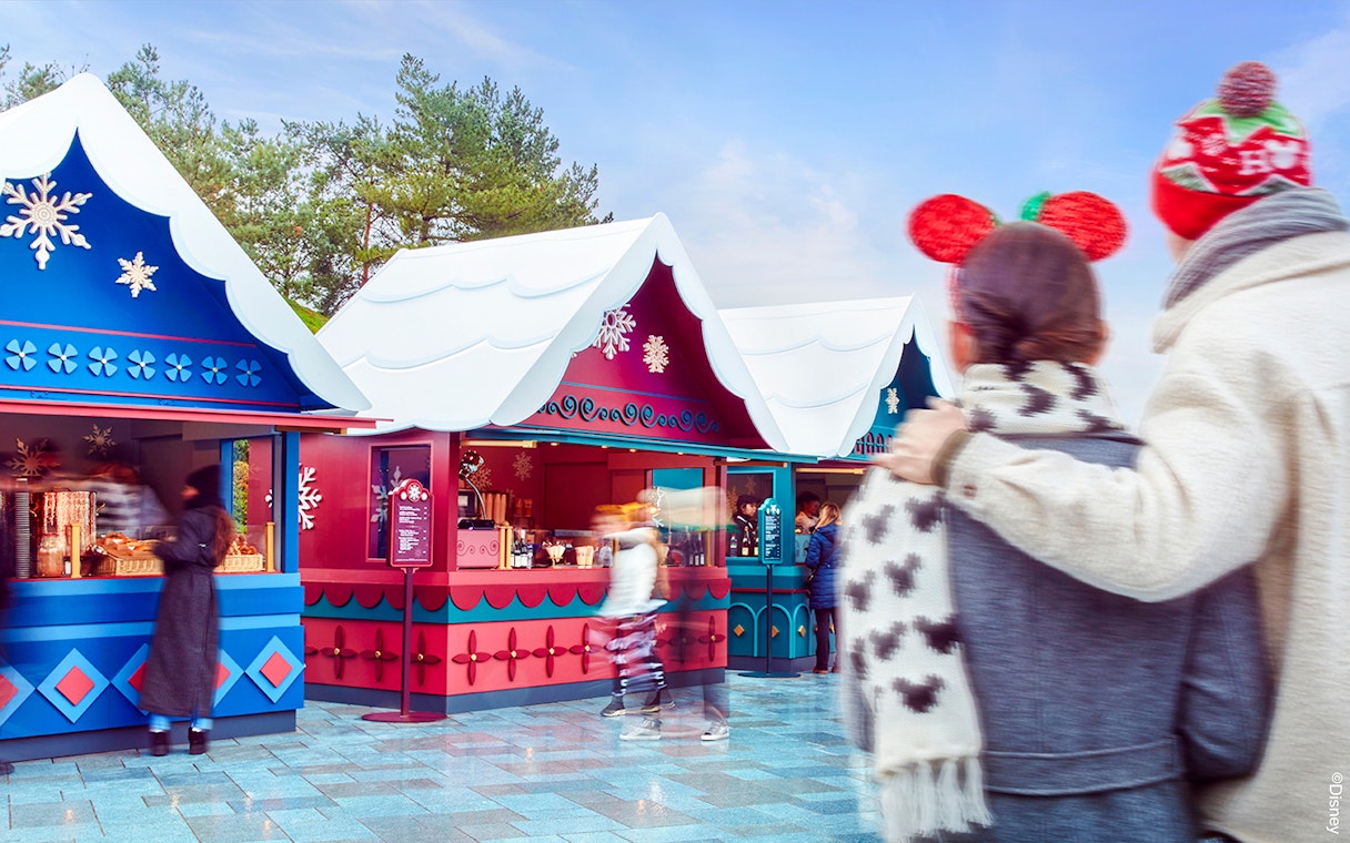 Disneyland Paris Christmas market stalls with visitors in festive attire, 2025.