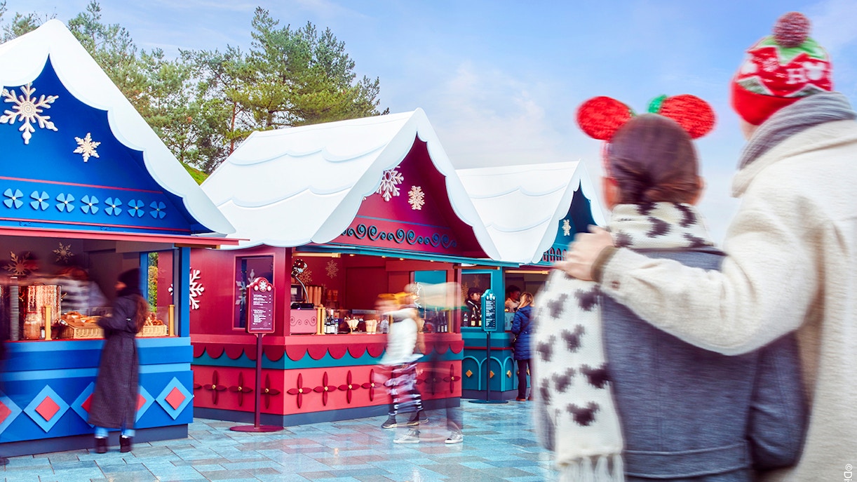 Disneyland Paris Christmas market stalls with visitors in festive attire, 2025.