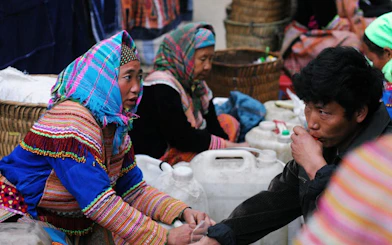 Bac Ha Market vendors selling corn wine in traditional attire, Vietnam.