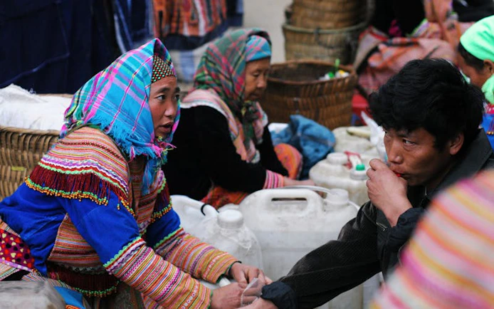 Bac Ha Market vendors selling corn wine in traditional attire, Vietnam.