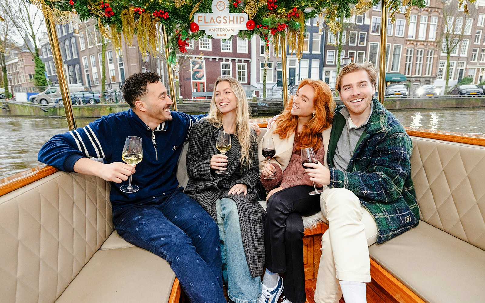 Friends enjoying wine on an evening canal cruise in Amsterdam.