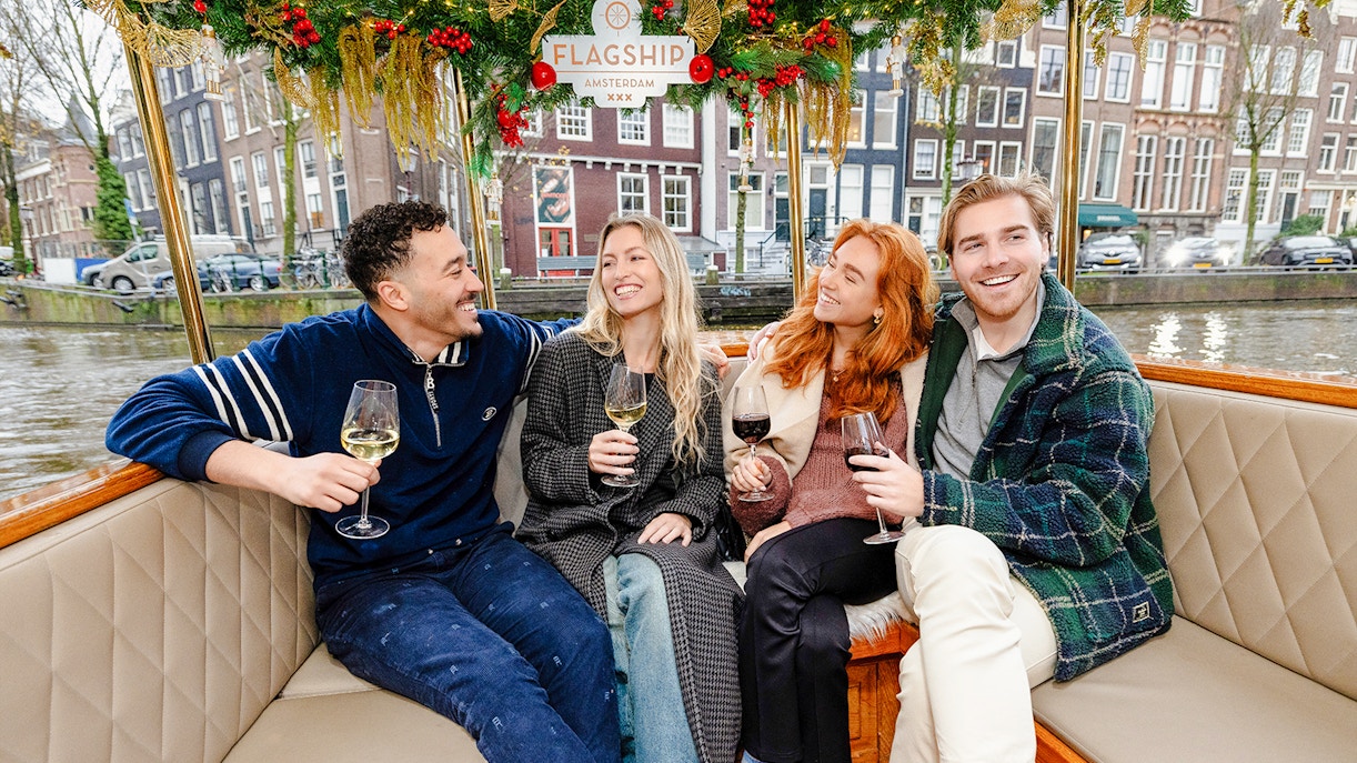 Friends enjoying wine on an evening canal cruise in Amsterdam.