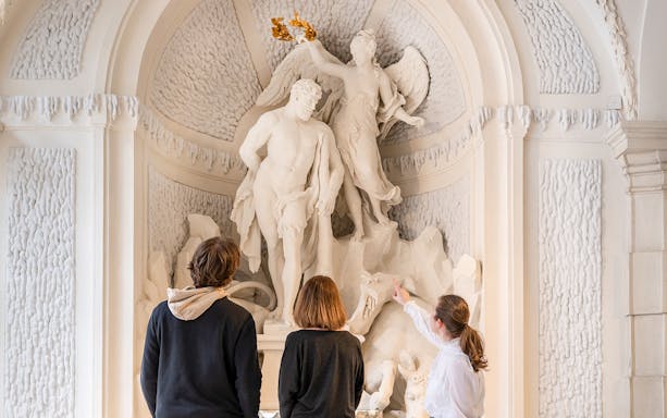 Visitors observing a detailed sculpture at Palais Lobkowitz during an audio guide tour.