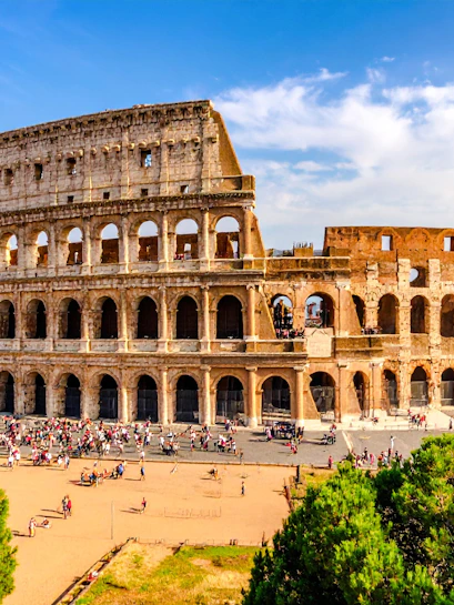 Wide view of the Colosseum in Rome with tourists exploring the ancient amphitheater.