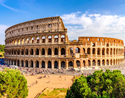 Wide view of the Colosseum in Rome with tourists exploring the ancient amphitheater.