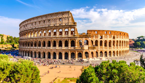 Wide view of the Colosseum in Rome with tourists exploring the ancient amphitheater.
