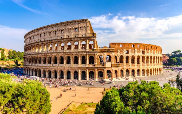 Wide view of the Colosseum in Rome with tourists exploring the ancient amphitheater.